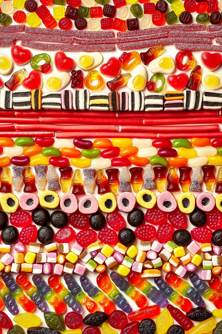 Rows of assorted sweets including gummy bears, jelly beans, liquorice allsorts, cola bottles and rainbow gummy snakes