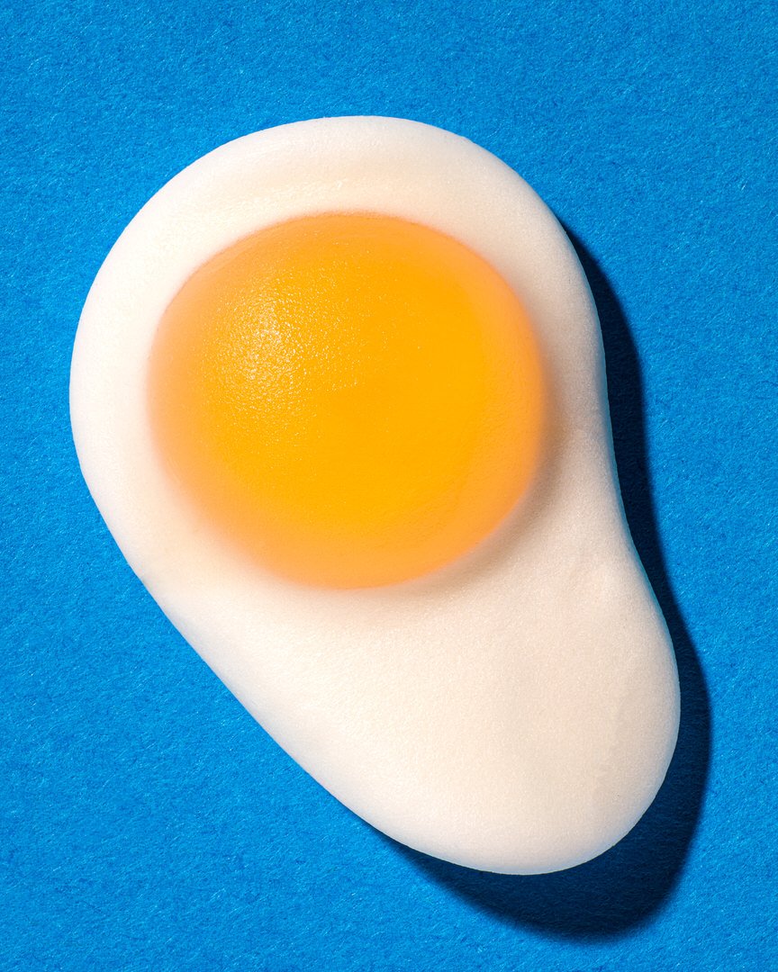 A fried egg with a bright orange yolk, viewed from above on a blue background