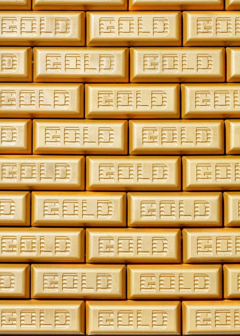 Rows of gold-coloured chocolate bars embossed with the word "GOLD", stacked in a repeating pattern