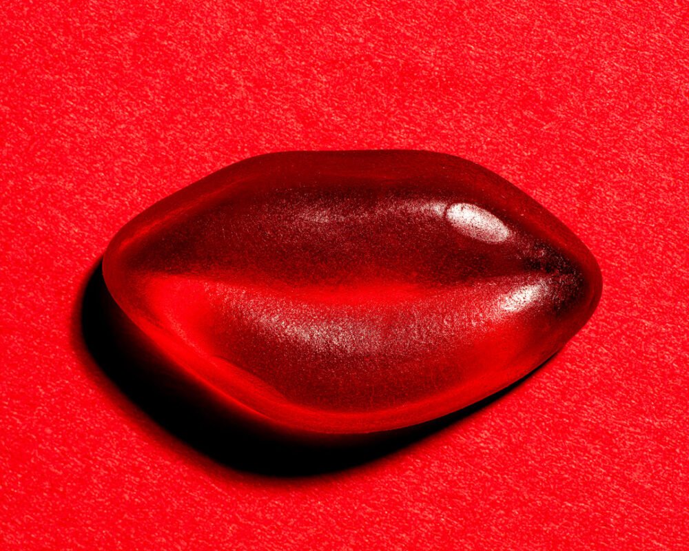 Close-up of a glossy red boiled sweet on a red textured background