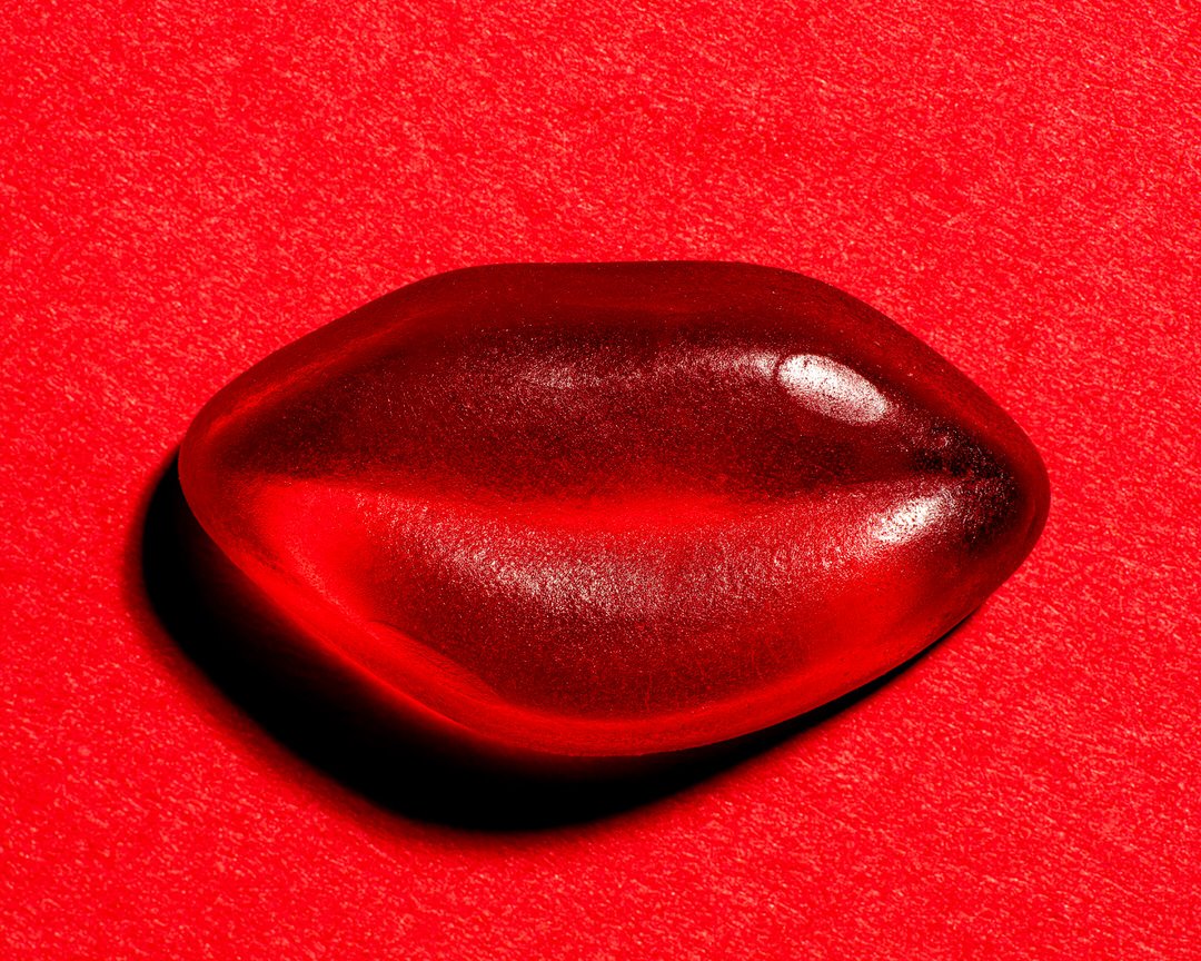 Close-up of a glossy red boiled sweet on a red textured background