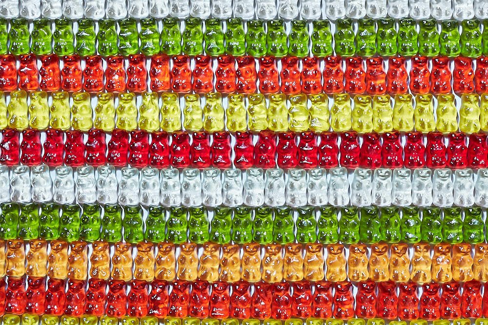Rows of gummy bear sweets arranged in horizontal stripes of different colours and flavours