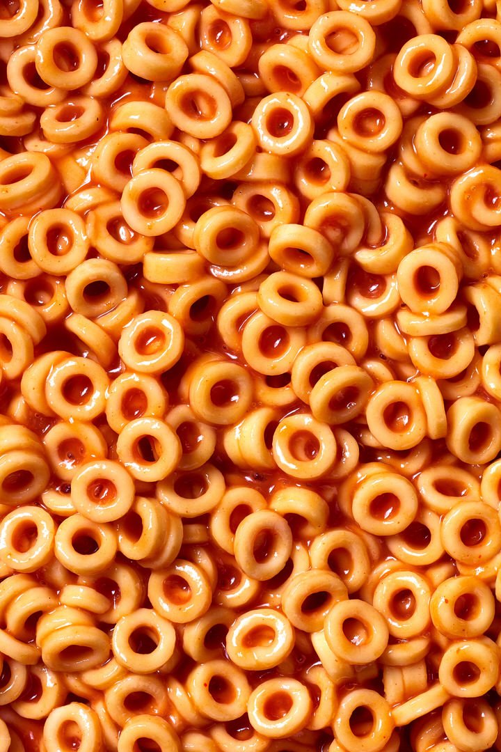 Close-up of ring-shaped pasta shapes in tomato sauce, filling the entire frame