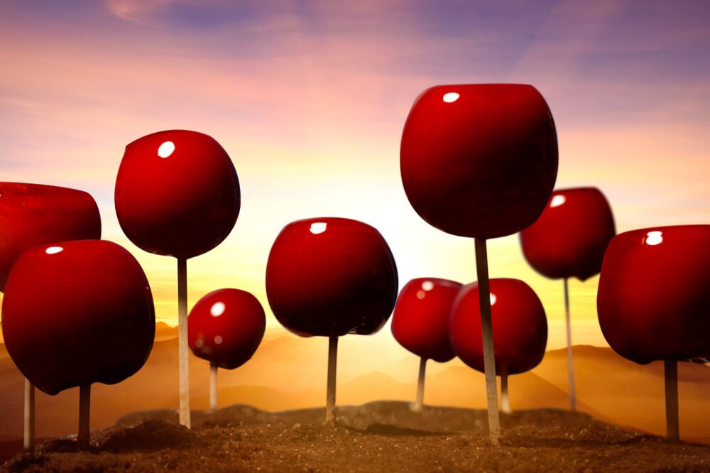 Digitally rendered scene of glossy red apple-shaped orbs on thin stems planted like trees, set against a sunset sky