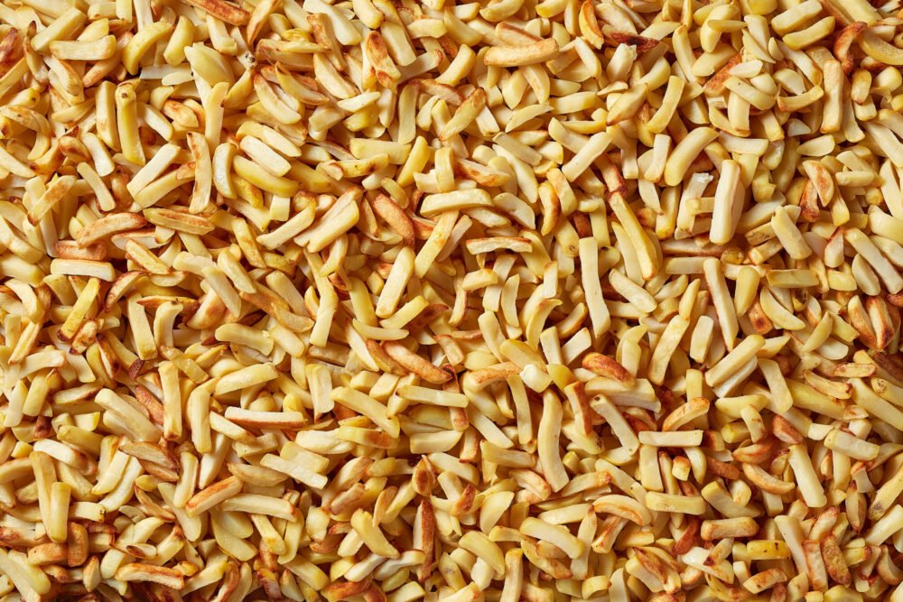 Close-up of golden fried potato chips covering the entire frame