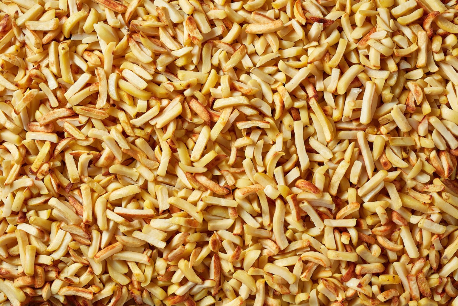 Close-up of golden fried potato chips covering the entire frame
