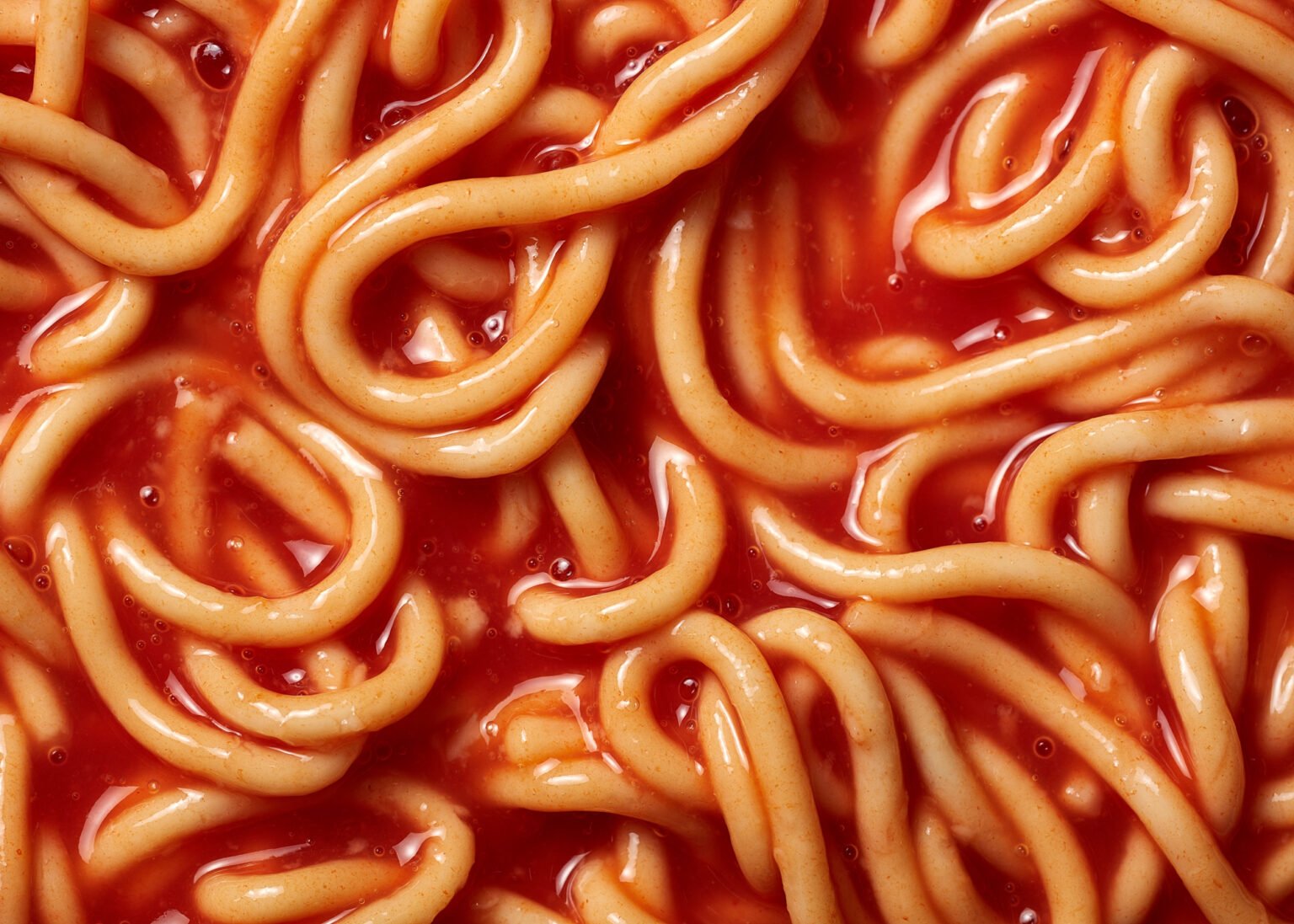Close-up of tinned spaghetti hoops-style noodles coated in thick tomato sauce