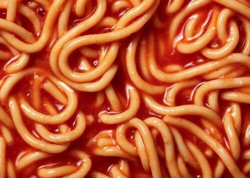 Close-up of tinned spaghetti hoops-style noodles coated in thick tomato sauce