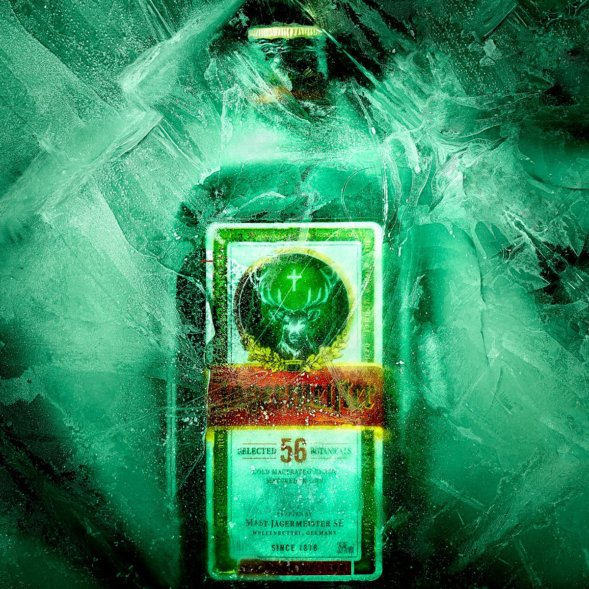 Bottle of Jägermeister with its stag-and-cross label encased in cracked ice, lit in green light