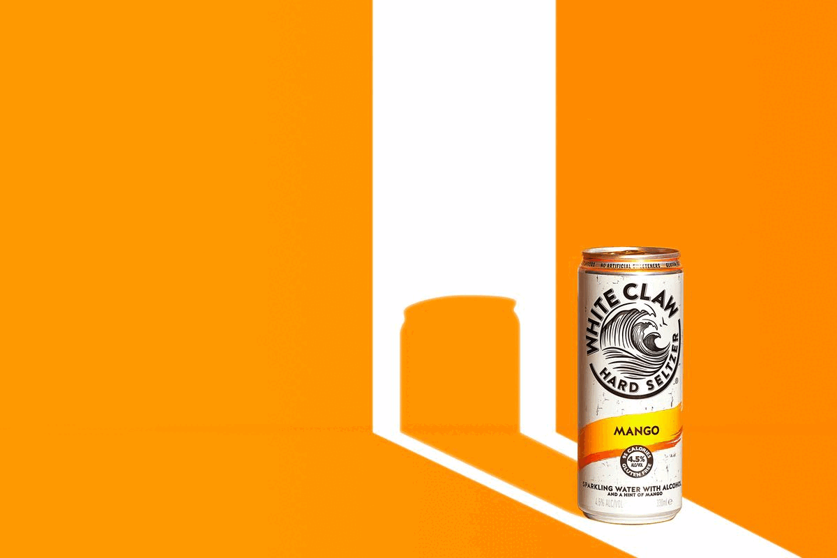Can of White Claw Hard Seltzer, Mango flavour, 4.5% ALC/VOL, against an orange background