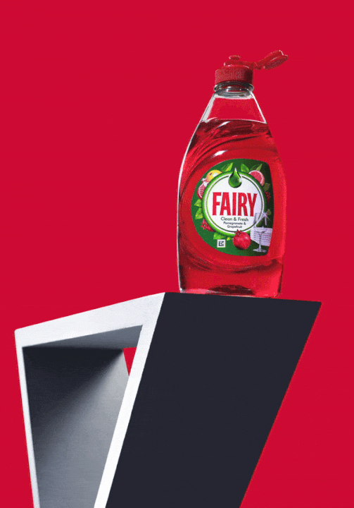 Bottle of Fairy Clean & Fresh washing-up liquid, Pomegranate and Grapefruit scent, on a red background