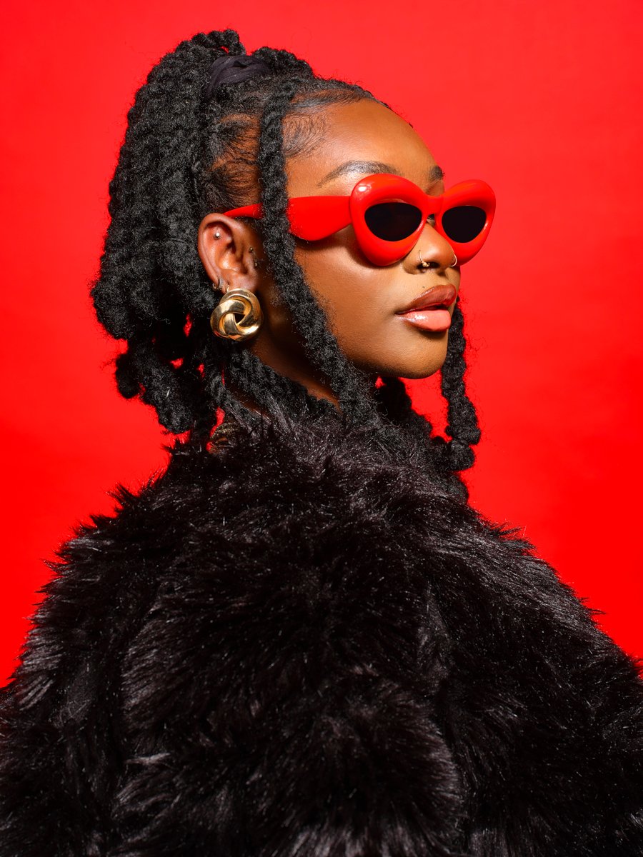 portrait by scott choucino of a model wearing bright red glasses on a bold and graphic red background.