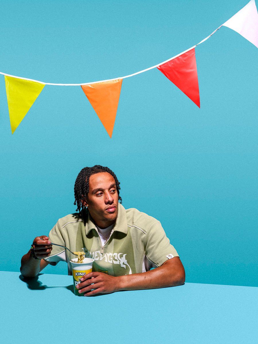 young man eating potnoodles at a birthday part with a bold and graphic background