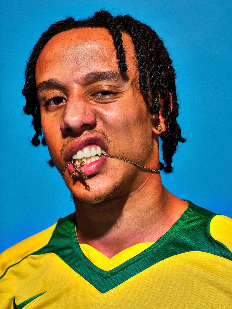pro footballer biting a chain photographed by scott choucino on a bright blue photographic background in his london studio