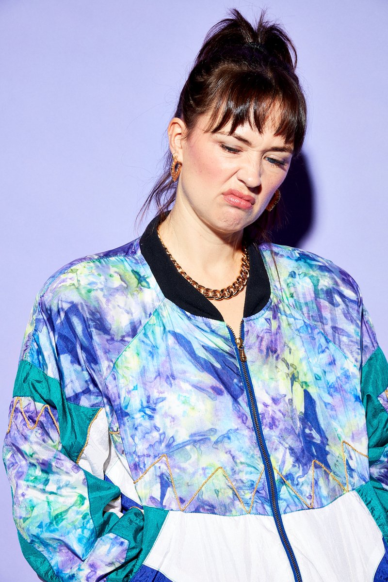 chav in a tracksuit photographed by commercial portrait photographer scott choucino on a purple background with a 80s tracksuit