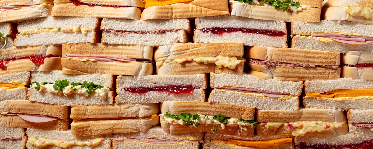 Rows of assorted finger sandwiches with fillings including ham, cheese, jam, egg mayonnaise and cress