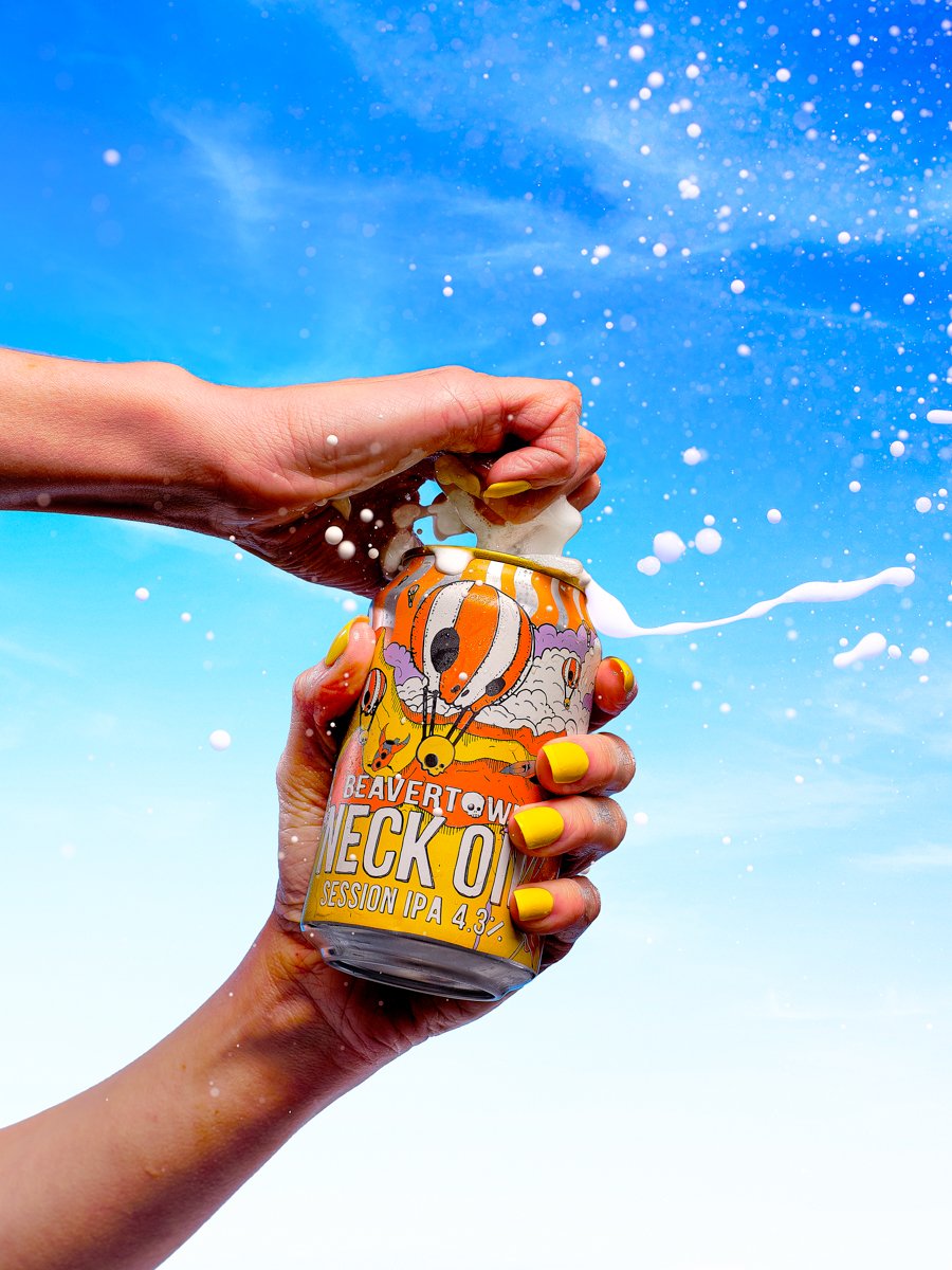 a can of bevertown beer being opened in front of a summer sky with beer exploding