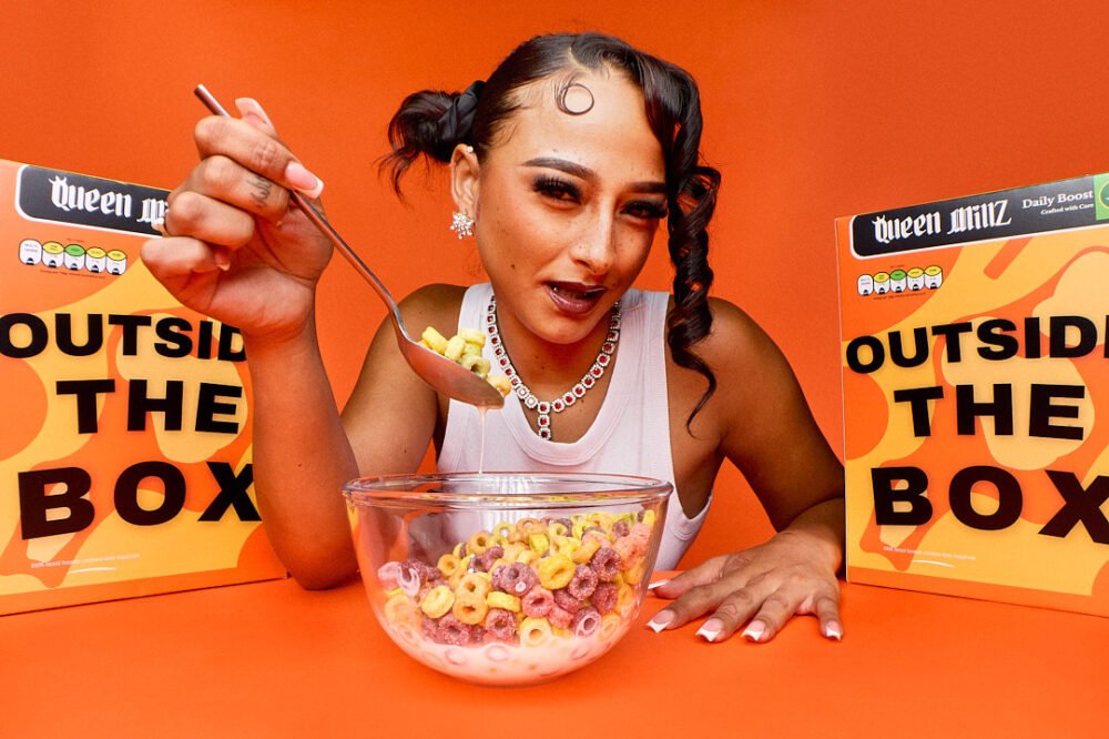 Portrait of a rapper eating cereal on a block coloured background with cereal boxes